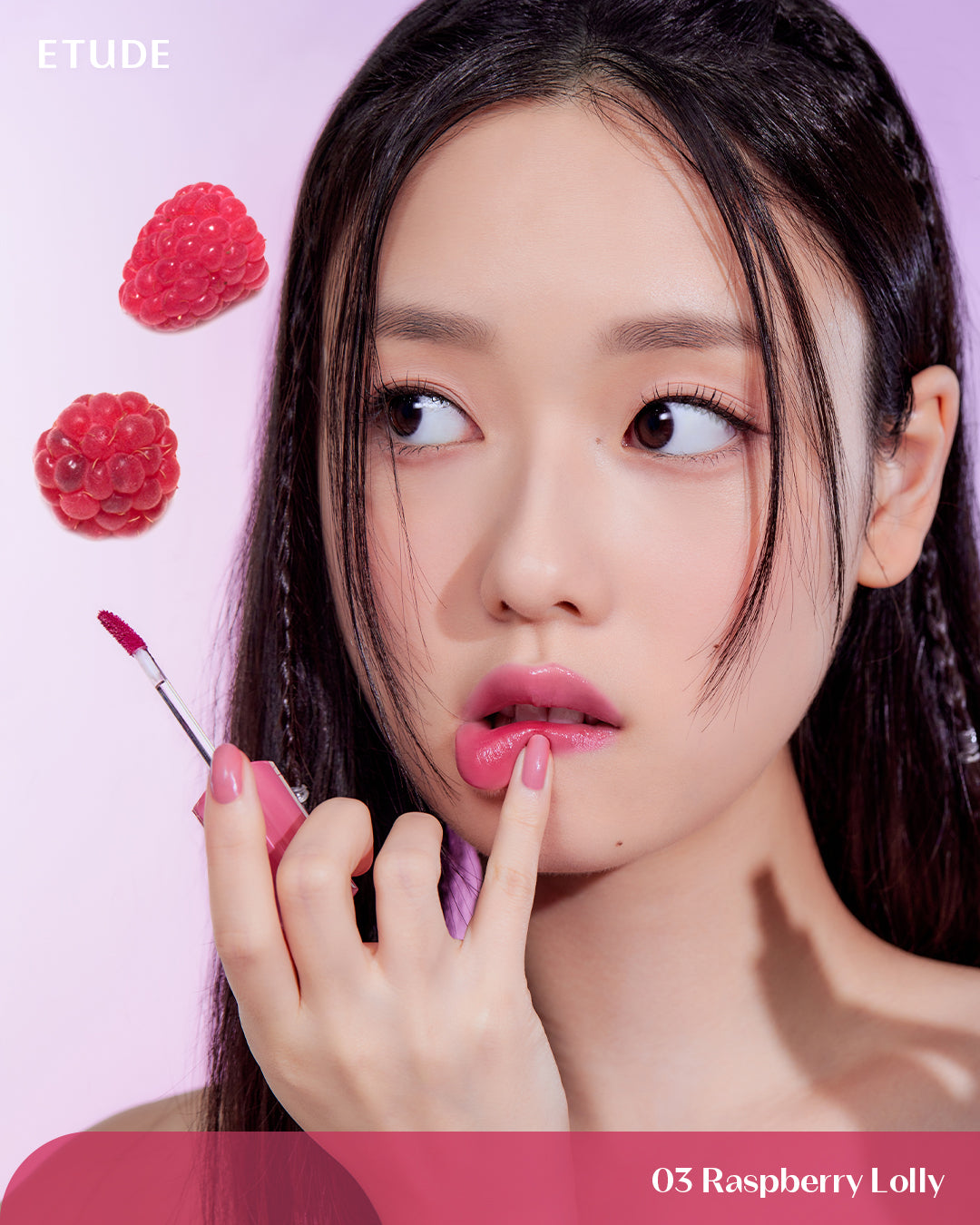Woman applying lipstick with raspberries on a pink background, featuring the ETUDE brand.